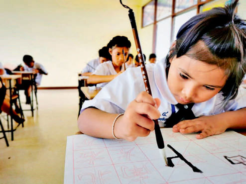 泰国孩子在中国志愿者指导下认真练习书法。（作者供图）